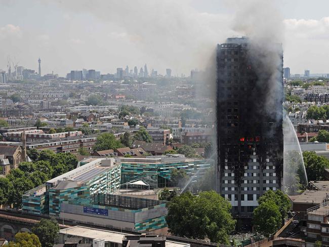 TOPSHOT - Smoke and flames billows from Grenfell Tower as firefighters attempt to control a blaze at a residential block of flats on June 14, 2017 in west London. At least six people were killed Wednesday when a massive fire tore through a London apartment block in the middle of the night, with witnesses reporting terrified people had leapt from the 24-storey tower. / AFP PHOTO / Adrian DENNIS