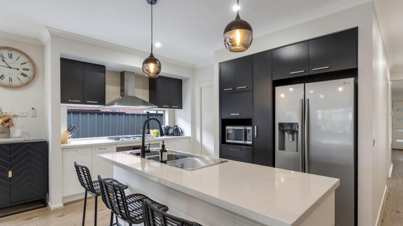 Black cabinetry, stone benchtops and a wide window splashback make this Craigieburn kitchen both stylish and functional.
