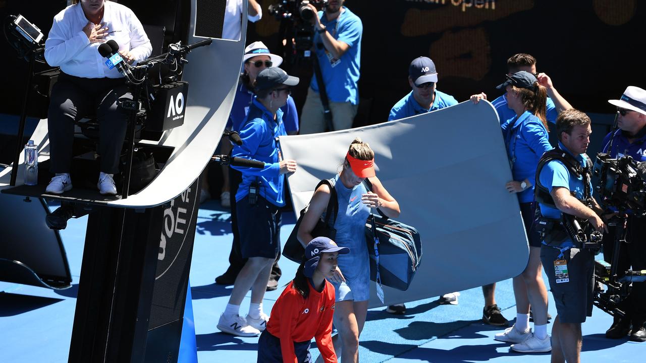 The broken canopy shade is carried off the court. Photo: William WEST / AFP