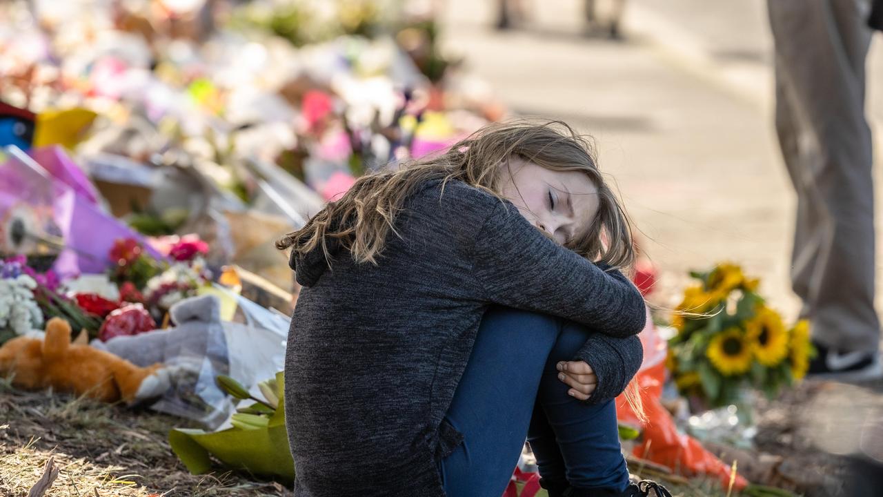 A young girl takes a moment after laying flowers outside Hillcrest Primary School. Picture: Jason Edwards