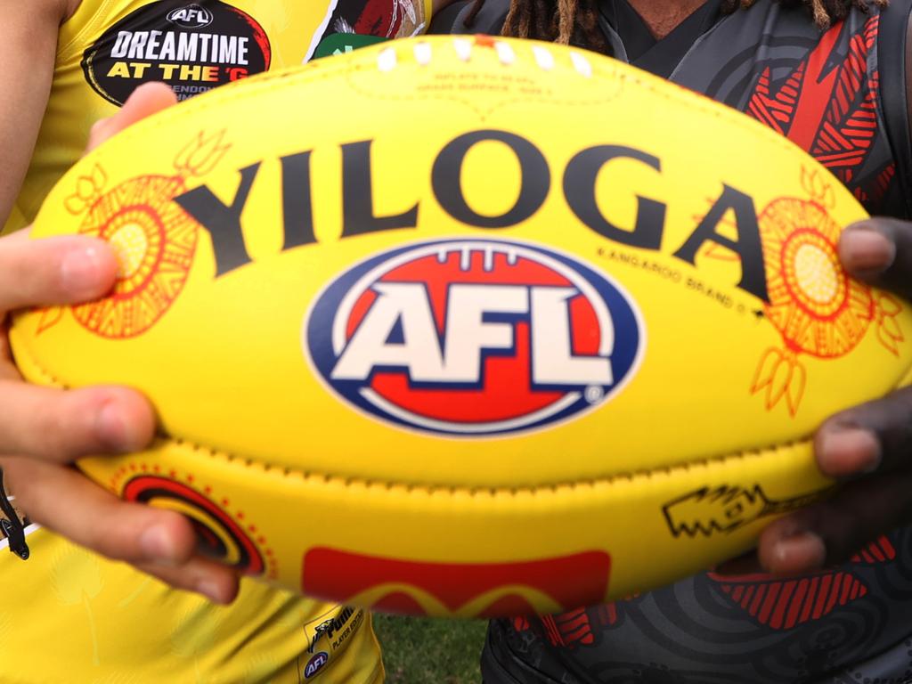 WARNING EMBARGO until Monday 15th MAY 2023. SEE PIC DESK Sherrin changing ball for Sir Doug Nicholls Round (Round 10) Indigenous AFL stars Daniel Rioli and Anthony McDonald-Tipungwuti, hold the SDNR Sherrin artwork designed by Tiwi woman Lulu Coombes. Picture: David Caird