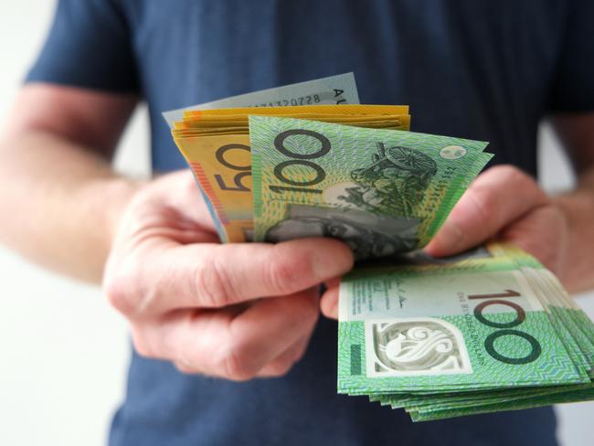 A man counting Australian dollar bills. A picture that describes buying, paying, handing out money, or showing money. Australian cash money generic