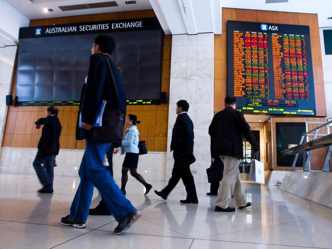 People walk in front of an electronic board which displays stock prices inside the Australia Securities Exchange (ASX Ltd.), building in Sydney, Australia, on Monday, Nov. 1, 2010. Singapore Exchange Ltd.'s A$8.1 billion ($8 billion) bid for ASX Ltd. will be vetted by Australia's Foreign Investment Review Board before approval, Prime Minister Julia Gillard said in an interview with the Australian Broadcasting Corp. Photographer: Ian Waldie/Bloomberg