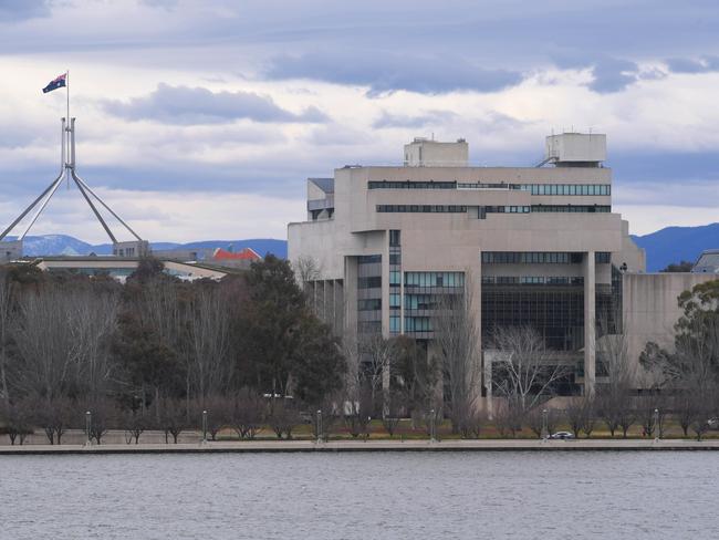 Parliament House is seen next to the High Court building on the shore of Lake Burley Griffin in Canberra, Monday, August 21, 2017. The High Court has been asked by Parliament to rule on the issue of citizenship under Section 44 regarding several federal politicians. (AAP Image/Lukas Coch) NO ARCHIVING