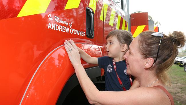 Andrew’s wife Melissa and daughter Charlotte help to adhere a decal commemorating their late husband and father on the new fire truck at Horsley Park. Picture: Robert Pozo