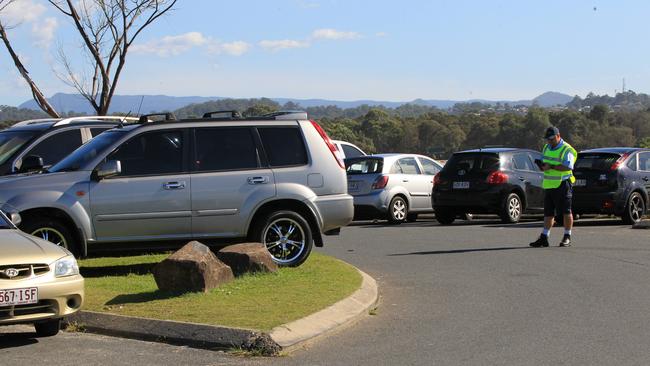 Gold Coast City Council parking inspectors pictured booking cars for parking on the grass at the popular swiming beach at the Currumbin Creek seaway entrance.