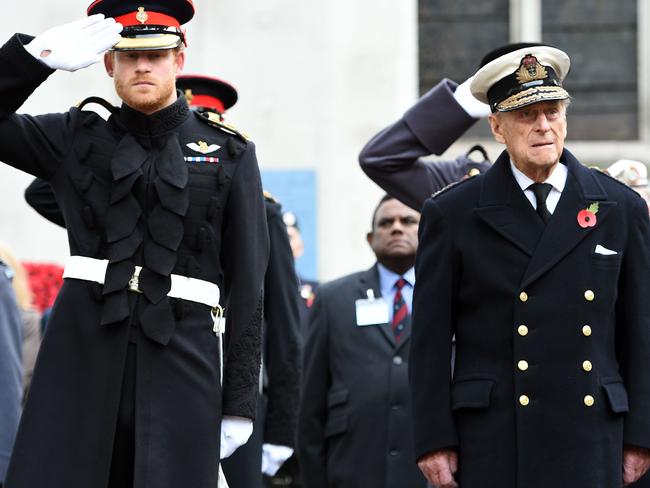 Britain's Prince Harry salutes as he stands alongside Prince Philip during their visit to the Field of Remembrance at Westminster Abbey in 2016. Picture: AFP