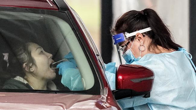 A medical worker takes a sample from a person at a drive-through COVID-19 pop-up testing clinic.