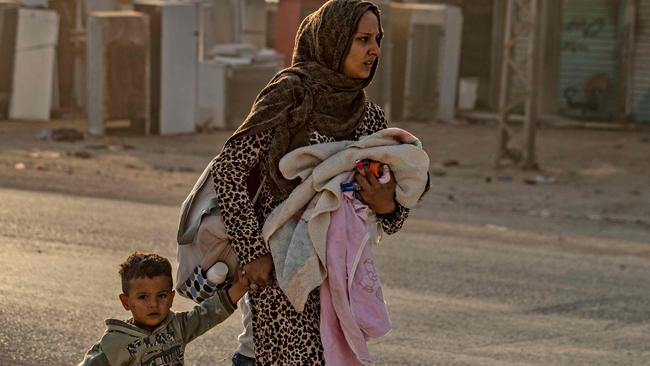 A woman flees Ras al-Ain with her children as the city is bombed. Picture: AFP.