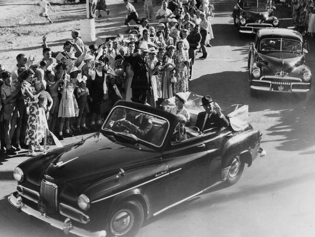 Queen Elizabeth II and Prince Philip promenade past a waving crowd of people in a Humber Pullman car in 1954.