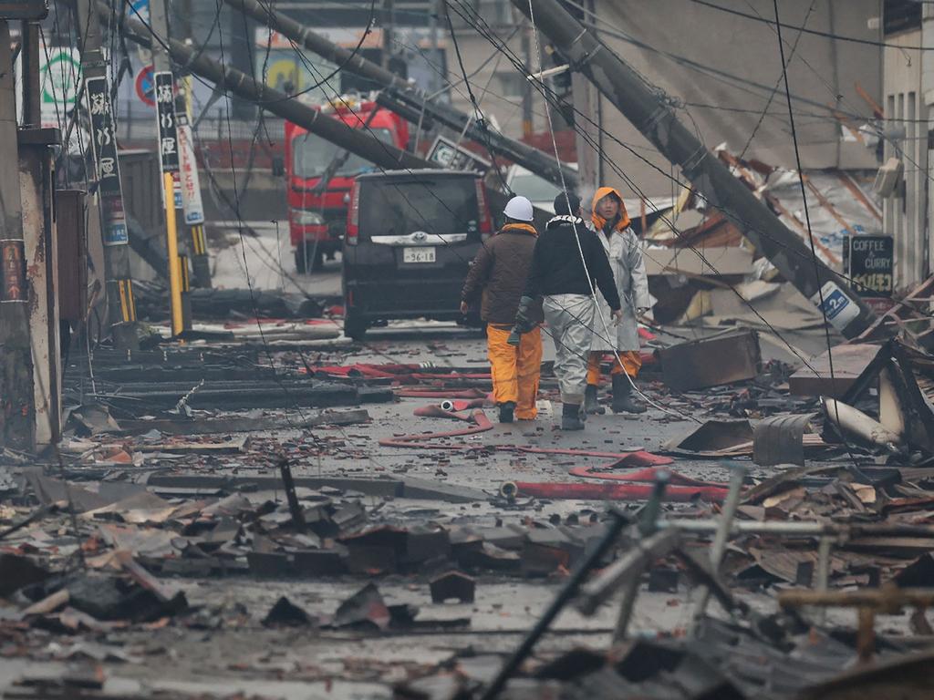 People walk through an area devastated by a quake-induced fire in the city of Wajima,. Picture: AFP