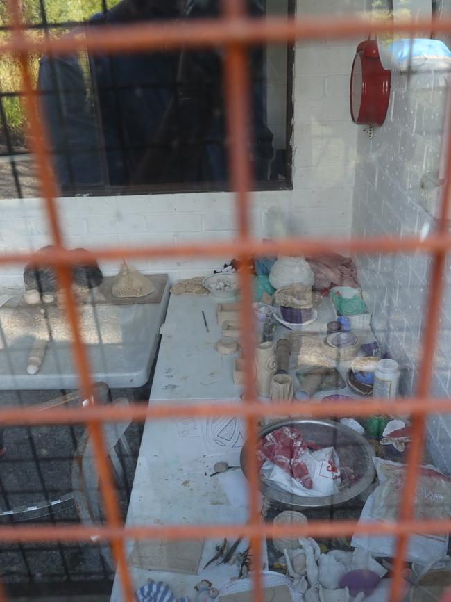 A window, covered in a metal cage, reveals pottery and arts and craft. Picture: David Swift.