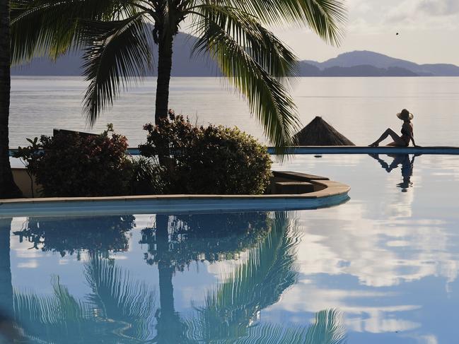 HAMILTON ISLAND Picture: istock One person sitting beside a tropical pool overlooking the Whitsunday Islands.