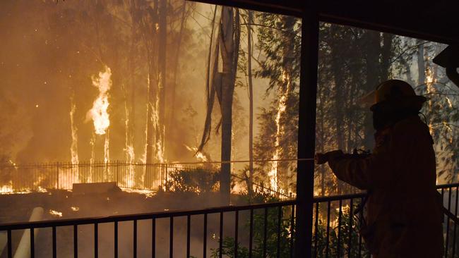 RFS volunteers and NSW Fire and Rescue officers protect a home on Wheelbarrow Ridge Road. Picture: Dean Lewins