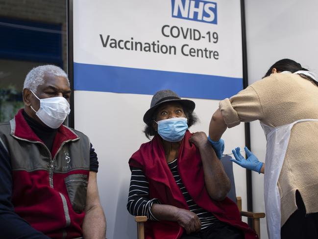 Lorna Lucas, 81, reacts as she receives the first of two Pfizer/BioNTech COVID-19 vaccine jabs shortly before her husband, Winston, left, also has one administered at Guy's Hospital, in central London. Picture: AFP