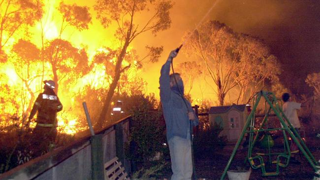 Firefighters and residents battle flames as fire threatened homes around Powderworks Rd at Ingleside in January, 2001. There are concerns the proposed redevelopment could hamper bushfire evacuations. Picture: John Grainger