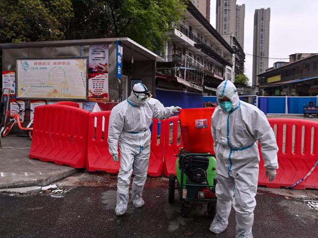 Workers wearing protective suits walking next to a wet market in Wuhan. Picture: AFP