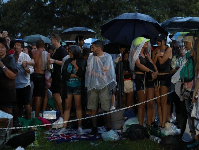 NYE revellers huddle under covers as heavy rains pass over sydney harbour Picture Jonathan Ng