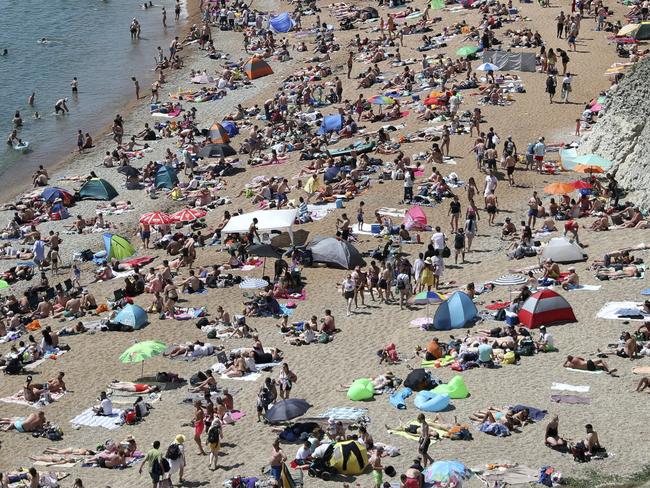 People on the beach at Durdle Door, as the public are being reminded to practice social distancing following the relaxation of coronavirus lockdown restrictions, near Lulworth in Dorset, England, Saturday, May 30, 2020.  (Andrew Matthews/PA via AP)