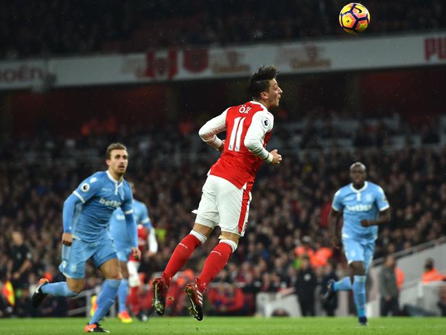 Ozil (C) heads the ball to score.