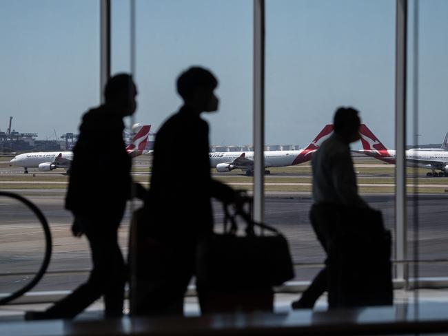 SYDNEY, AUSTRALIA - NewsWire Photos December 9, 2020: Qantas aircraft seen on the runway as passengers passes through the terminal in the foreground at Sydney International Airport. Picture: NCA NewsWire / James Gourley