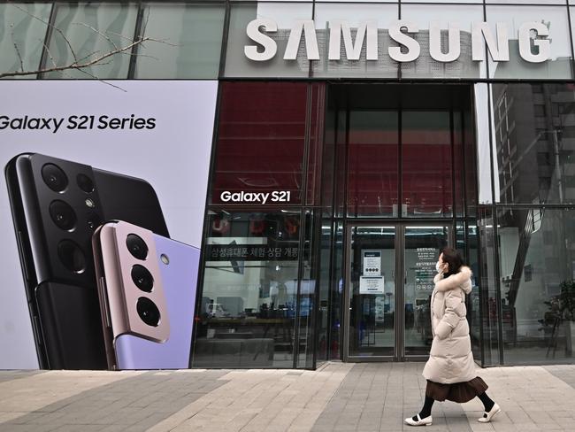 A woman walks past an advertisement for the Samsung Galaxy S21 smartphone at a Samsung Electronics store in Seoul on January 28, 2021, after the company reported its fourth-quarter net profits up by more than a quarter year-on-year. (Photo by Jung Yeon-je / AFP)