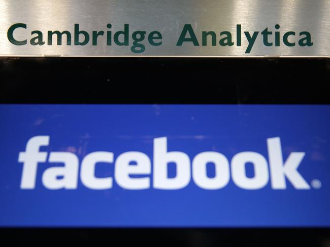 A laptop showing the Facebook logo is held alongside a Cambridge Analytica sign. Picture: AFP