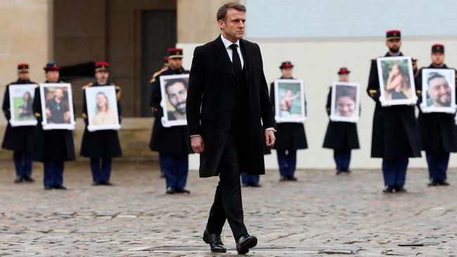 Emmanuel Macron leads a ceremony at Les Invalides, where victims’ photographs were held aloft by troops. Picture: AFP