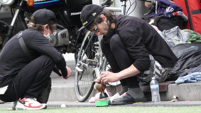 Homeless people lighting a bong near the corner of Elizabeth and Flinders streets last December. Picture: Alex Coppel