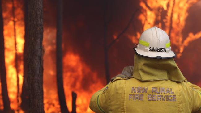 A NSWRFS volunteer in front of a large bushfire. Picture: Jake McCallum