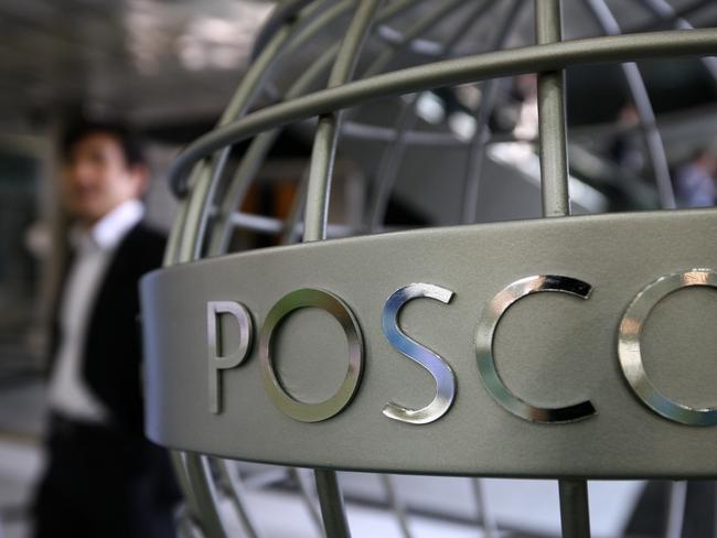 A man walks past the Posco logo displayed on a steel structure outside the company's showroom in Seoul, South Korea, on Friday, April 20, 2012. Posco, the world's third-biggest steelmaker by output, said first-quarter profit fell 42 percent because of rising raw-material costs and waning demand for the metal used in cars, ships and buildings. Photographer: SeongJoon Cho/Bloomberg