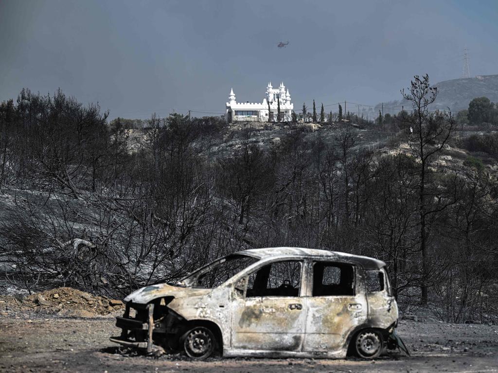 A burnt car sits in foreground of a charred area after a fire near the village of Kiotari, on the Greek island of Rhodes. Picture: AFP