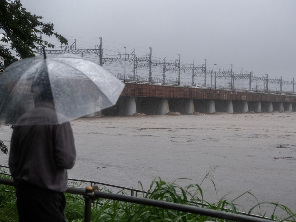 A man shelters under an umbrella as he looks at the flooded Tama River. Picture: Getty