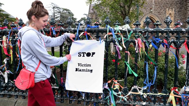 Holly Baker hangs a sign on the wrought-iron fence outside St Patrick’s Cathedral in Ballarat on Tuesday. Picture: David Geraghty