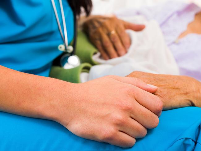 Social care provider holding senior hands in caring attitude - helping elderly people. istock