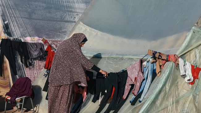 A woman hangs up clothes at a camp in Rafah in the southern Gaza Strip on December 16. Picture: AFP