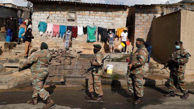 People stand near their home and watch as members of the South African Defence Force patrol their area in Alexandra township, Johannesburg. Picture: AFP