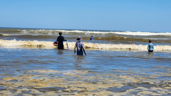 Kids swim in dirty-brown waves at Middleton Beach on Saturday, January 7.