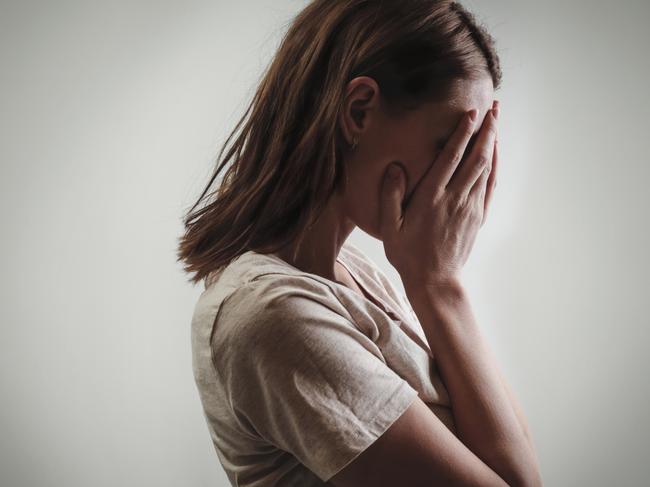 Portrait of depressed woman, covering face with her hands, side view