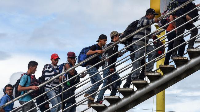 Honduran migrants climb an overpass to go to Tecum Uman, Guatemalan border with Mexico, in Guatemala City, on October 18, 2018. - US President Donald Trump threatened Thursday to send the military to close its southern border if Mexico fails to stem the "onslaught" of migrants from Central America, in a series of tweets that blamed Democrats ahead of the midterm elections. (Photo by ORLANDO SIERRA / AFP)