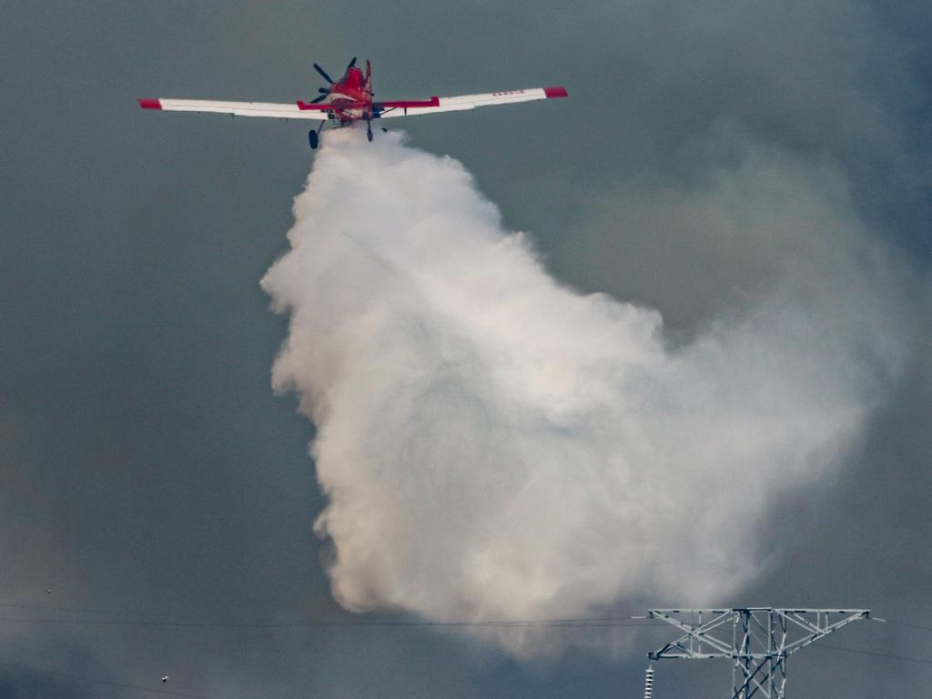 Firefighting aircraft and Firefighters defend Power infrastructure from an out of control fire in Berrimah. Picture: Glenn Campbell.