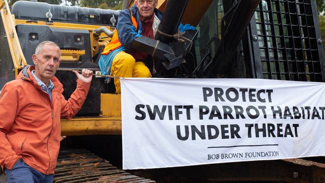 Bob Brown with forest defender attached to logging equipment. Bob Brown Foundation forest defenders have returned to contentious Eastern Tiers forests after three arrests yesterday. Logging of habitat for critically endangered Swift Parrots has been halted for a second day. Picture: BOB BROWN FOUNDATION