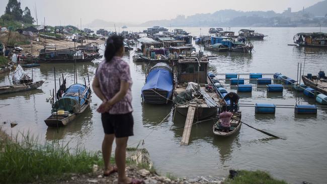 <s1>A woman from the Tanka looks at boats moored on a river in Datang, in southern China's Guangdong province</s1>. <source>Picture: AFP PHOTOS</source>                                             <source/>