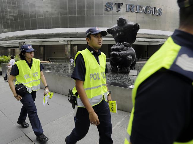 FILE - In this June 9, 2018, file photo, Singapore police officers patrol the grounds around the St. Regis Hotel as traffic policemen start to barricade the roads surrounding it, in Singapore ahead of the summit between U.S. President Donald Trump and North Korean leader Kim Jong Un. Kim is on a rare trip abroad as he leaves the all-encompassing bubble of his locked-down stronghold of Pyongyang and steps off a jet onto Singaporean soil for his planned sit-down with Trump on Tuesday, June 12, 2018. (AP Photo/Wong Maye-E, File)