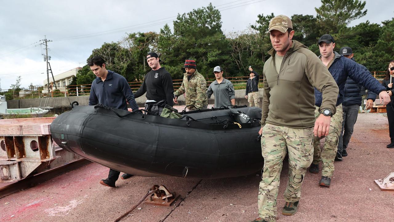 US military personnel carry a dinghy as they head out to search. Picture: JIJI Press / AFP