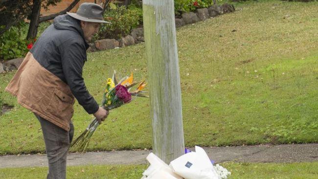 A man lays flowers at a floral tribute at the crime scene. Picture: NewsWire / Jeremy Piper