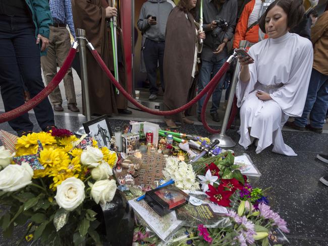 Victoria Schmidt, right, dressed as Princess Leia, in honour of actress Carrie Fisher, takes photos of an impromptu memorial created on a blank Hollywood Walk of Fame star. Picture: AP