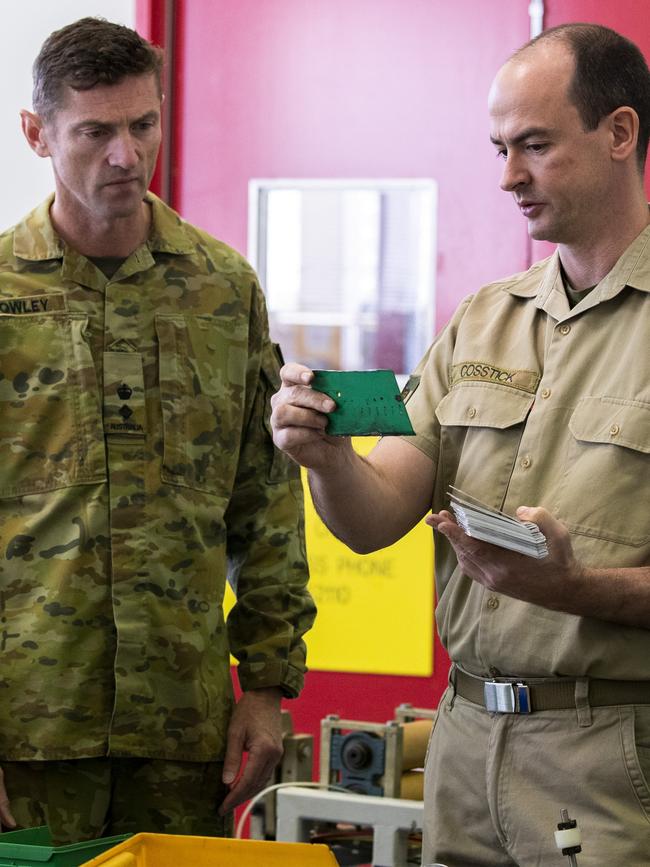 Army officer Lieutenant Colonel Nathan Crowley (left) and Warrant Officer Class Two Steven Cosstick, discuss actions for replacing a part for a civilian machine being repaired at Wadsworth Barracks, east of Wodonga in Victoria.