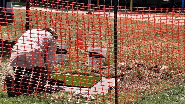 A Port Macquarie-Hastings Council worker covering the metal plate in astroturf the day after the incident at Westport water park.