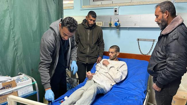 A Palestinian prisoner speaks with doctors at the European Hospital in Khan Yunis in the southern Gaza Strip early on February 27, 2025, following his release by Israeli authorities. Hamas handed over the coffins of four hostages early on February 27, Israeli authorities confirmed, followed soon after by the return of hundreds of freed Palestinian prisoners to the West Bank and Gaza. In the West Bank and Gaza, AFP journalists saw hundreds of Palestinian prisoners freed by Israel arrive on buses accompanied by Red Cross vehicles. More than 600 were due to be released in the latest exchange, while Al Jazeera reported nearly 100 would be deported to Egypt. (Photo by AFP)